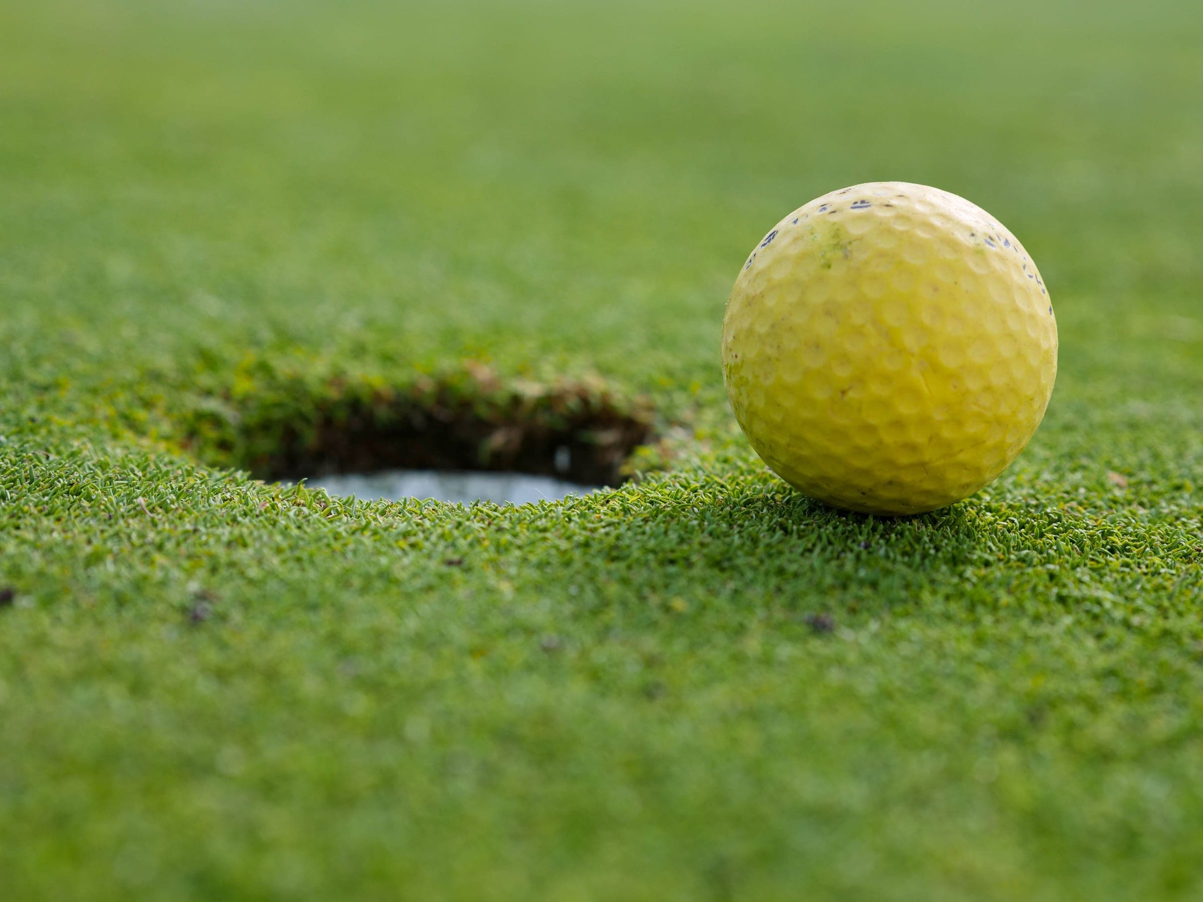 A golf ball at the lip of the hole